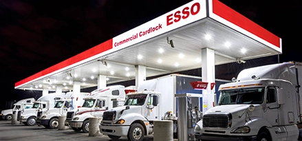 Photo of transport trucks parked under Esso cardlock canopy at night