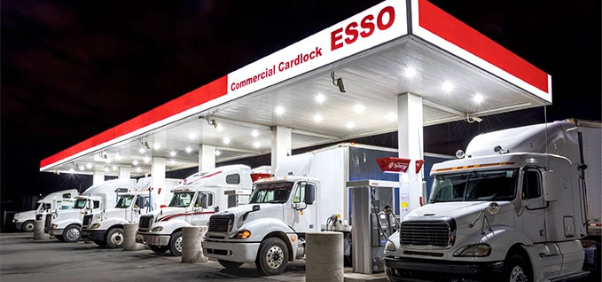 Photo de camions de transport garés sous le auvent de la station-service Esso la nuit