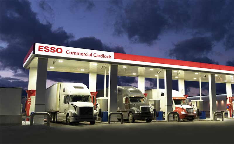 Photo of transport trucks parked under Esso cardlock canopy at night